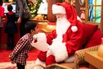 Kid slightly bowing to a seated Santa Claus