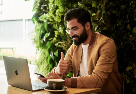Bearded gentleman giving the thumbs up while working on a laptop